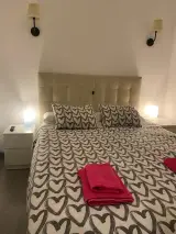 Interior apartment bedroom from the foot of the bed with radiator, drawer wardrobe and flat-screen TV on the right wall